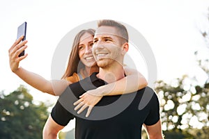 Young happy millennial couple smiling and taking selfie - Z generation tourists having fun together - Technology concept with a