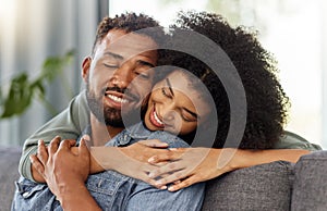 Young happy mixed race couple embracing while relaxing at home. Hispanic boyfriend and girlfriend smiling while hugging