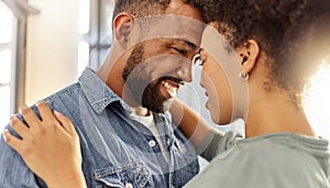 Young happy mixed race couple hugging while relaxing at home. Cozy hispanic husband and wife smiling while staring into