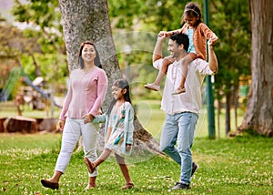 Young happy mixed race family relaxing and walking together in a park. Loving hispanic parents spending time with their