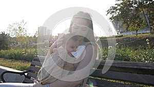 Young happy mom with baby girl in ergo backpack in the Park