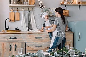 Young happy mom and her baby cook cookies at home in the kitchen. Christmas Homemade Gingerbread. cute boy with mother