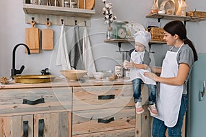 Young happy mom and her baby cook cookies at home in the kitchen. Christmas Homemade Gingerbread. cute boy with mother