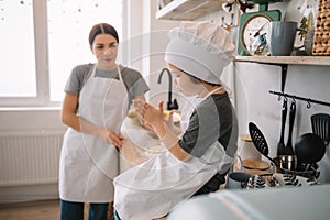 Young happy mom and her baby cook cookies at home in the kitchen. Christmas Homemade Gingerbread. cute boy with mother in white