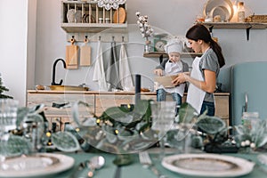 Young happy mom and her baby cook cookies at home in the kitchen. Christmas Homemade Gingerbread. cute boy with mother in white