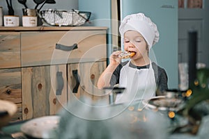 Young happy mom and her baby cook cookies at home in the kitchen. Christmas Homemade Gingerbread. cute boy with mother in white