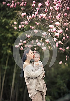 Young and happy mother cares for her young son, and walks along the shore of the lake in the summer in the park