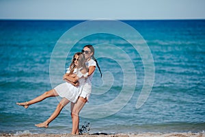 Young happy mother and and her daughter having fun on the beach