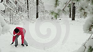 Young happy mother and her little daughter playing with snow balls in forest.