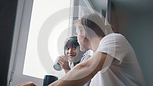 Young happy multiracial couple drinking coffee or tea and looking through the window. Slow motion