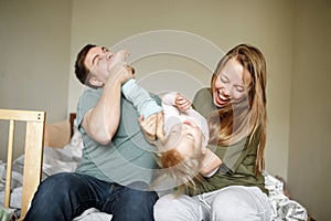 Young happy parents playing with their toddler funny joyful girl