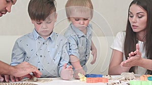 Young happy parents showing their children how to make cookies