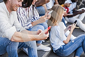 Young happy people using mobile phones outdoor in the city - Focus on left man hand holding smartphone