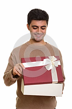 Young happy Persian man opening gift box ready for Valentine`s d