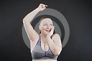 Young happy plus size caucasian woman shows her unshaved armpit