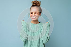 Young happy positive emotional attractive blonde woman with sincere emotions wearing casual blue sweater isolated on