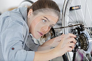 young happy positive woman master repairing bicycle in workshop photo