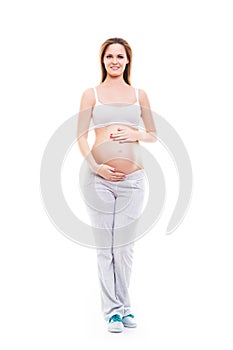 A young and happy pregnant woman posing in white sporty clothes