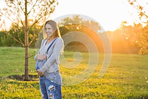 Young happy pregnant woman relaxing and enjoying life in autumn nature