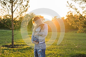 Young happy pregnant woman relaxing and enjoying life in autumn nature