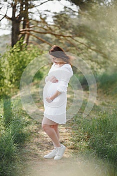 Young happy pregnant woman relaxing and enjoying life in nature. Outdoor shot. Copyspace