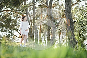 Young happy pregnant woman relaxing and enjoying life in nature. Outdoor shot. Copyspace