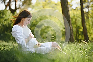 Young happy pregnant woman relaxing and enjoying life in nature. Outdoor shot. Copyspace