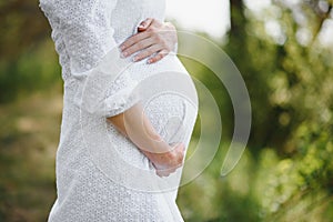 Young happy pregnant woman relaxing and enjoying life in nature. Outdoor shot. Copyspace