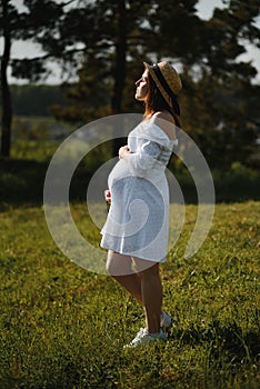 Young happy pregnant woman relaxing and enjoying life in nature. Outdoor shot. Copyspace