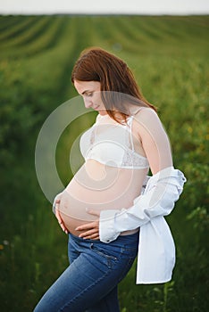 Young happy pregnant woman relaxing and enjoying life in nature. Outdoor shot. Copyspace