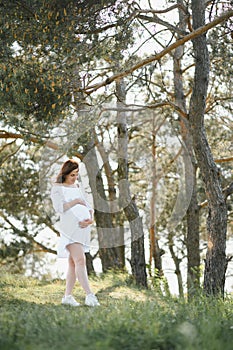 Young happy pregnant woman relaxing and enjoying life in nature. Outdoor shot. Copyspace