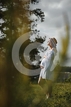 Young happy pregnant woman relaxing and enjoying life in nature. Outdoor shot. Copyspace