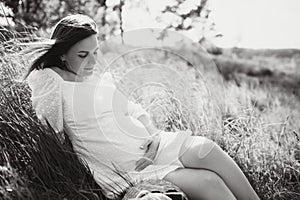 Young happy pregnant woman relaxing and enjoying life in nature. Outdoor shot. Copyspace