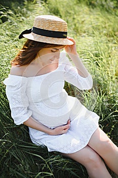 Young happy pregnant woman relaxing and enjoying life in nature. Outdoor shot. Copyspace