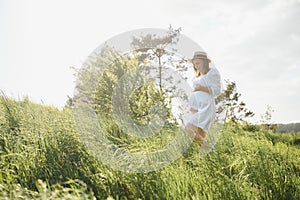 Young happy pregnant woman relaxing and enjoying life in nature. Outdoor shot. Copyspace