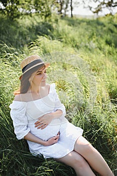 Young happy pregnant woman relaxing and enjoying life in nature. Outdoor shot. Copyspace