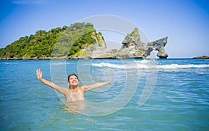 Young happy and pretty Asian Korean tourist woman enjoying swimming at tropical paradise beach island with tourquoise cyan sea wat