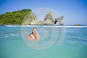 Young happy and pretty Asian Korean tourist woman enjoying swimming at tropical paradise beach island with tourquoise cyan sea wat