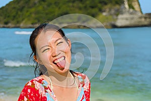 Young happy and pretty tourist Asian Korean woman in Summer dress enjoying tropical paradise beach holidays posing playful in fron