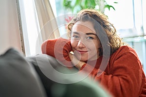 Young happy pretty woman relaxing sitting on couch at home. Portrait