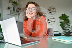 Young happy pretty woman student sitting at home office with laptop. Portrait