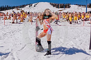 Young happy pretty women on a snowboard in colorful bikini.