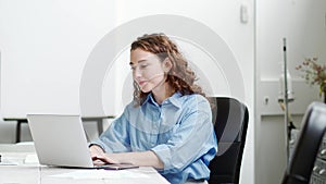 Young happy professional business woman sitting at desk working on laptop.