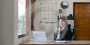 Young happy professional business woman worker employee sitting at desk working on laptop in corporate office. Smiling