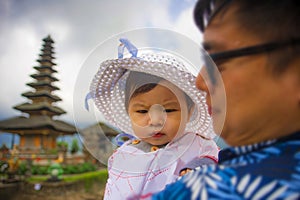 Young happy and proud Asian Chinese man as loving father holding adorable daughter baby girl during holidays excursion visiting