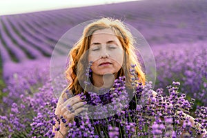 Young and happy redhead woman posing in the lavender field garden,