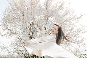 Young happy relaxed smiling beautiful woman in light casual clothes turning around standing in city garden or park on