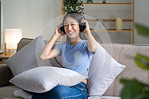 Young happy relaxing rest chilling woman sit on sofa listen to music song, happy life