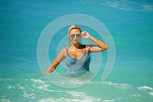 Young happy and sexy blond woman in bikini playing with waves in the sea at stunning beautiful tropical beach enjoying carefree