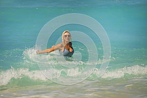 Young happy and sexy blond woman in bikini playing with waves in the sea at stunning beautiful tropical beach enjoying carefree